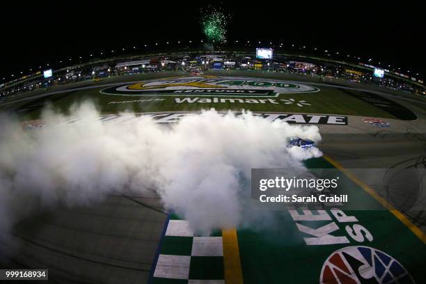 Martin Truex Jr., driver of the Auto-Owners Insurance Toyota, celebrates with a burnout after winning the Monster Energy NASCAR Cup Series Quaker...