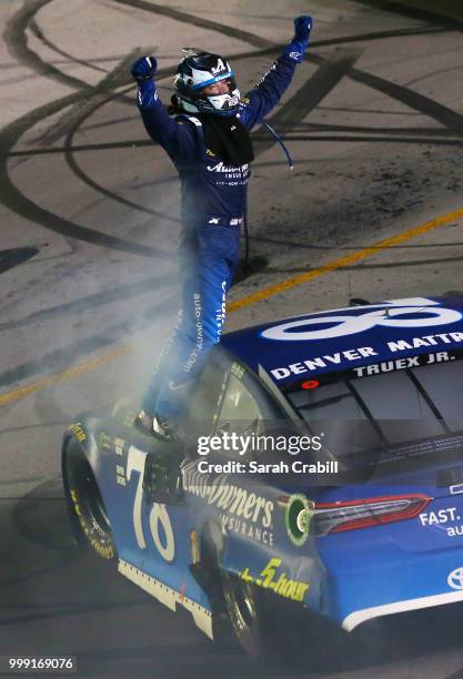 Martin Truex Jr., driver of the Auto-Owners Insurance Toyota, celebrates winning the Monster Energy NASCAR Cup Series Quaker State 400 presented by...