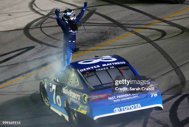 Martin Truex Jr., driver of the Auto-Owners Insurance Toyota, celebrates winning the Monster Energy NASCAR Cup Series Quaker State 400 presented by...