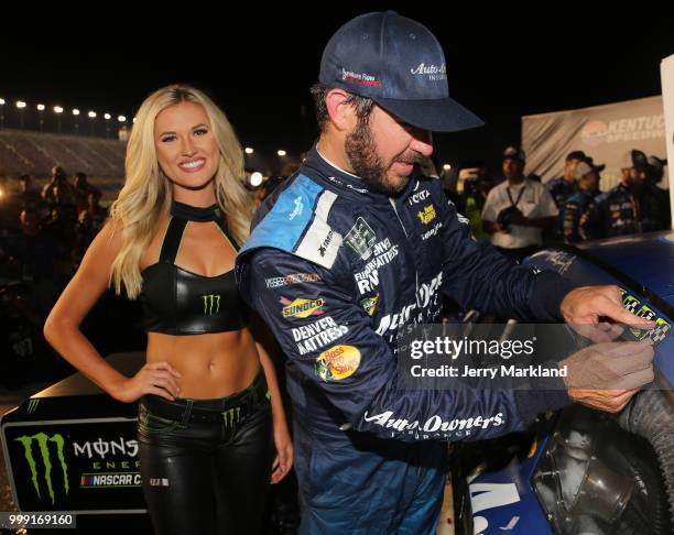 Martin Truex Jr., driver of the Auto-Owners Insurance Toyota, poses with the winner's decal in Victory Lane after winnin the Monster Energy NASCAR...