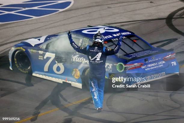 Martin Truex Jr., driver of the Auto-Owners Insurance Toyota, celebrates winning the Monster Energy NASCAR Cup Series Quaker State 400 presented by...