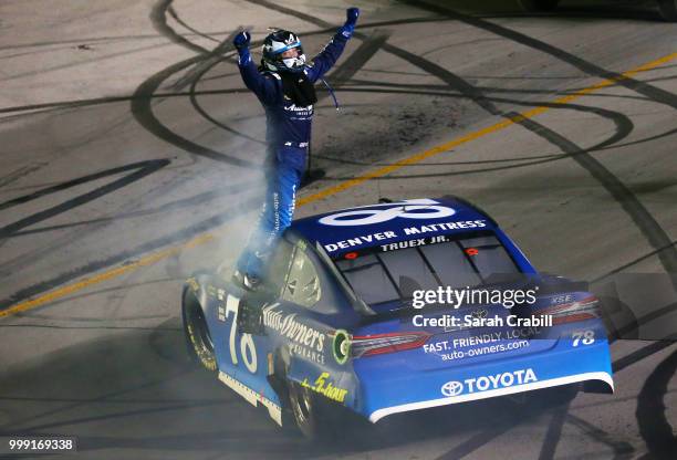 Martin Truex Jr., driver of the Auto-Owners Insurance Toyota, celebrates winning the Monster Energy NASCAR Cup Series Quaker State 400 presented by...