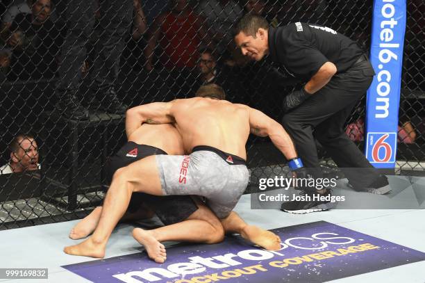 Referee Jason Herzog waits to call a stoppage as Chad Mendes punches Myles Jury after knocking him down in their featherweight fight during the UFC...