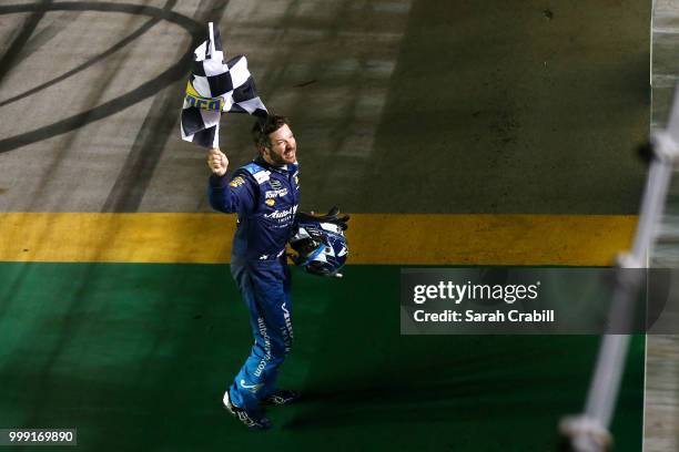 Martin Truex Jr., driver of the Auto-Owners Insurance Toyota, celebrates winning the Monster Energy NASCAR Cup Series Quaker State 400 presented by...