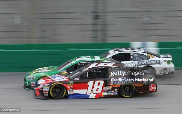 Kyle Busch, driver of the Snickers Intense Toyota, races Paul Menard, driver of the Menards/Quaker State Ford, and Erik Jones, driver of the...