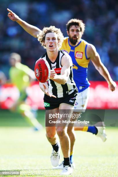 Chris Mayne of the Magpies handballs away from Josh Kennedy of the Eagles during the round 17 AFL match between the Collingwood Magpies and the West...