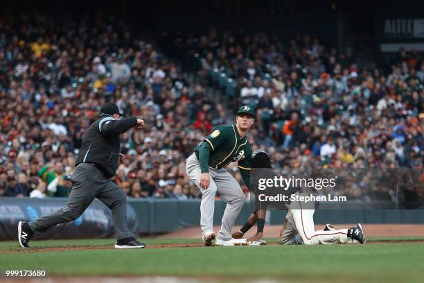 Alen Hanson of the San Francisco Giants is being tagged out at third on a steal attempt during the second inning against the Oakland Athletics at...
