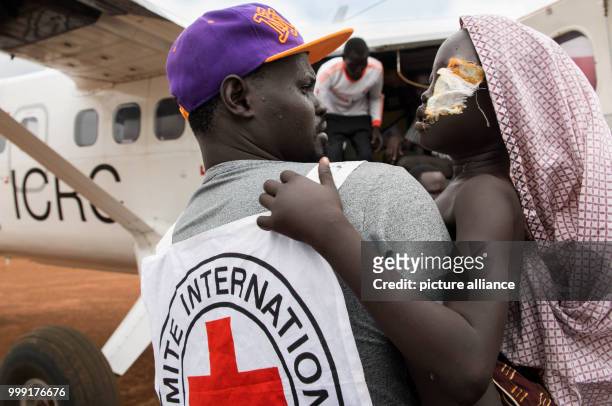 Member of the International Committee of the Red Cross carries 9-year-old Remaik to a plane to evacuate her to Juba, in Bor, South Sudan, 18 July...