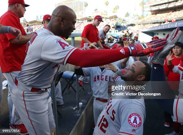 Justin Upton of the Los Angeles Angels of Anaheim celebrates with teammate Martin Maldonado in the dugout after Upton hit a solo homerun in the...