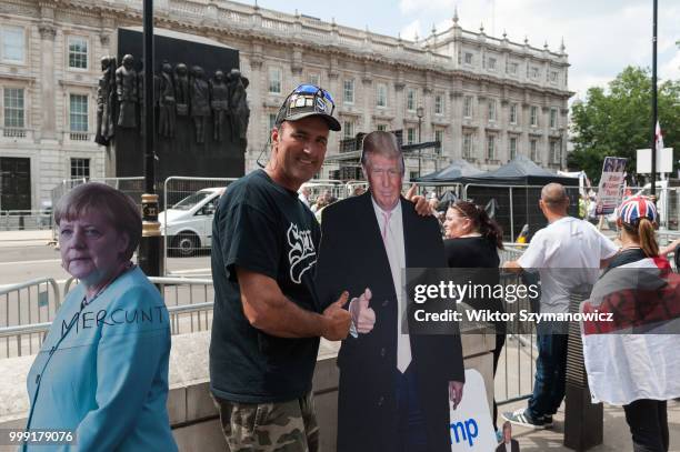 Canadian man poses with a cardbord cut outs of US president Donald Trump and German Chancellor Angela Merkel as supporters of far-right activist and...