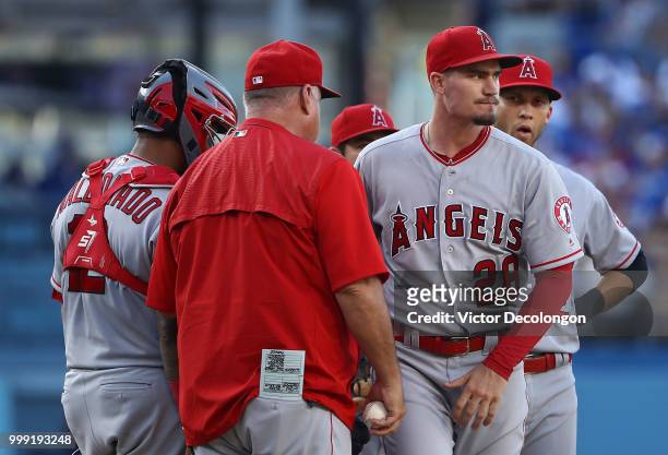 Pitcher Andrew Heaney of the Los Angeles Angels of Anaheim turns to walk to the dugout after handing the ball to manager Mike Scioscia in the seventh...