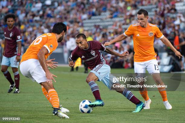 Edgar Castillo of Colorado Rapids dribbles between Kevin Garcia and Luis Gil of Houston Dynamo at Dick's Sporting Goods Park on July 14, 2018 in...