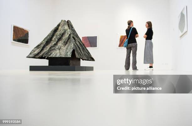 Two women seen next to a bronze pyramid by artist Emil Cimiotti from 1991 during a press preview of the 'Emil Cimiotti' exhibition at the Sprengel...