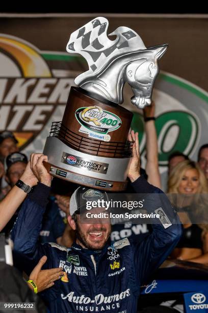 Martin Truex Jr., driver of the Auto-Owners Insurance Toyota, celebrates with the trophy after winning the Monster Energy NASCAR Cup Series Quaker...
