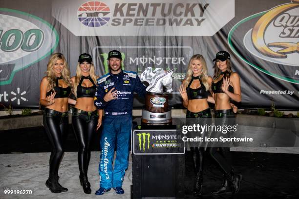 Martin Truex Jr., driver of the Auto-Owners Insurance Toyota, poses with the Monster Energy girls as they hold up four fingers to signify his four...