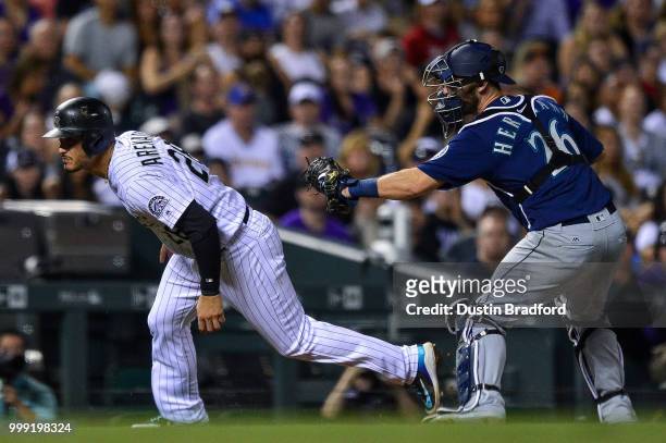Nolan Arenado of the Colorado Rockies is tagged out by Chris Herrmann of the Seattle Mariners on a fifth inning fielder's choice play at Coors Field...