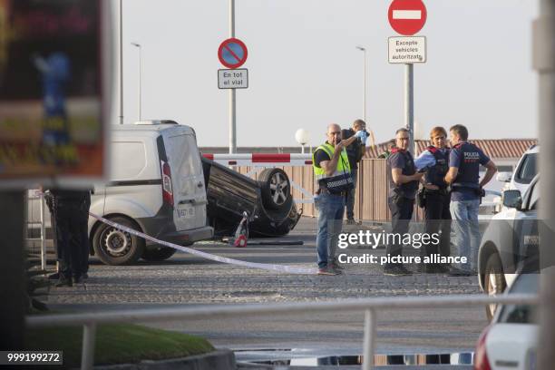 Police officers speaking next to a rolled over car at the location where police shot dead five terrorists in Cambrils, Spain, 18 August 2017. Police...