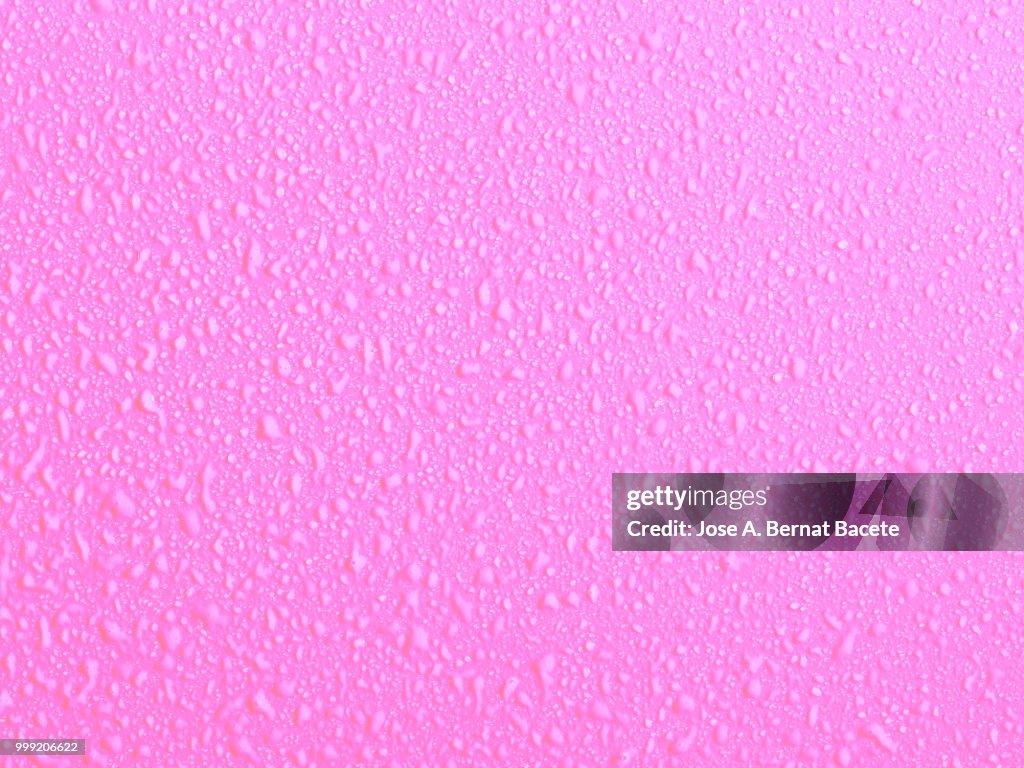 Full frame of the textures formed by the bubbles and drops of water, on a smooth light pink background.