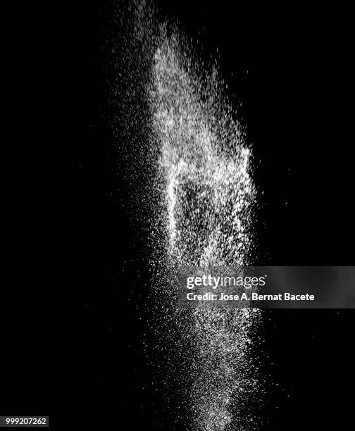 explosion by an impact of a cloud of particles of powder of color white on a black background. - bernat bacete stock-fotos und bilder