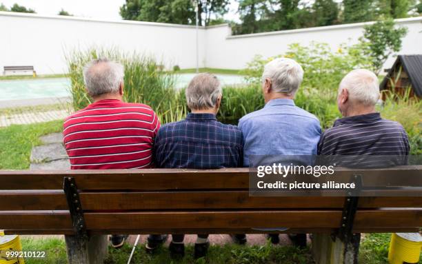 Four inmates of the prison sit on a bench in the courtyard of the jail in Singen, Germany, 27 July 2017. All four of them are senior citizens....