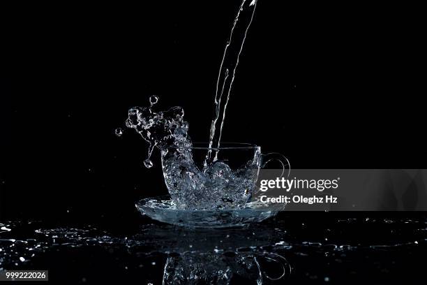 water pours into the cup on a black background, studio light - splash crown stock pictures, royalty-free photos & images
