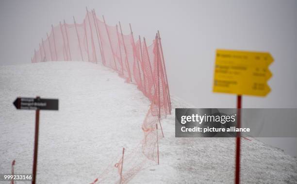 Signposts can be seen in the rain and fog at glacier of the Zugspitze in Grainau, Germany, 19 August 2017. Photo: Sven Hoppe/dpa