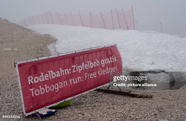 Sign saying 'Rodelbahn: Zipfelbob gratis' can be seen at the glacier in the rain and fog at the Zugspitze in Grainau, Germany, 19 August 2017. Photo:...