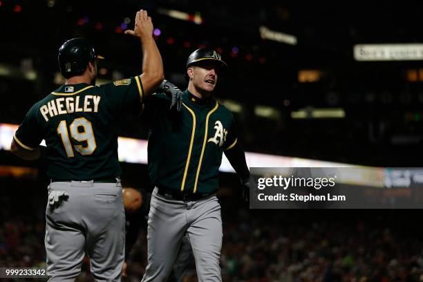 Mark Canha of the Oakland Athletics high-fives teammate Josh Phegley after hitting a two-run home run during the seventh inning against the San...