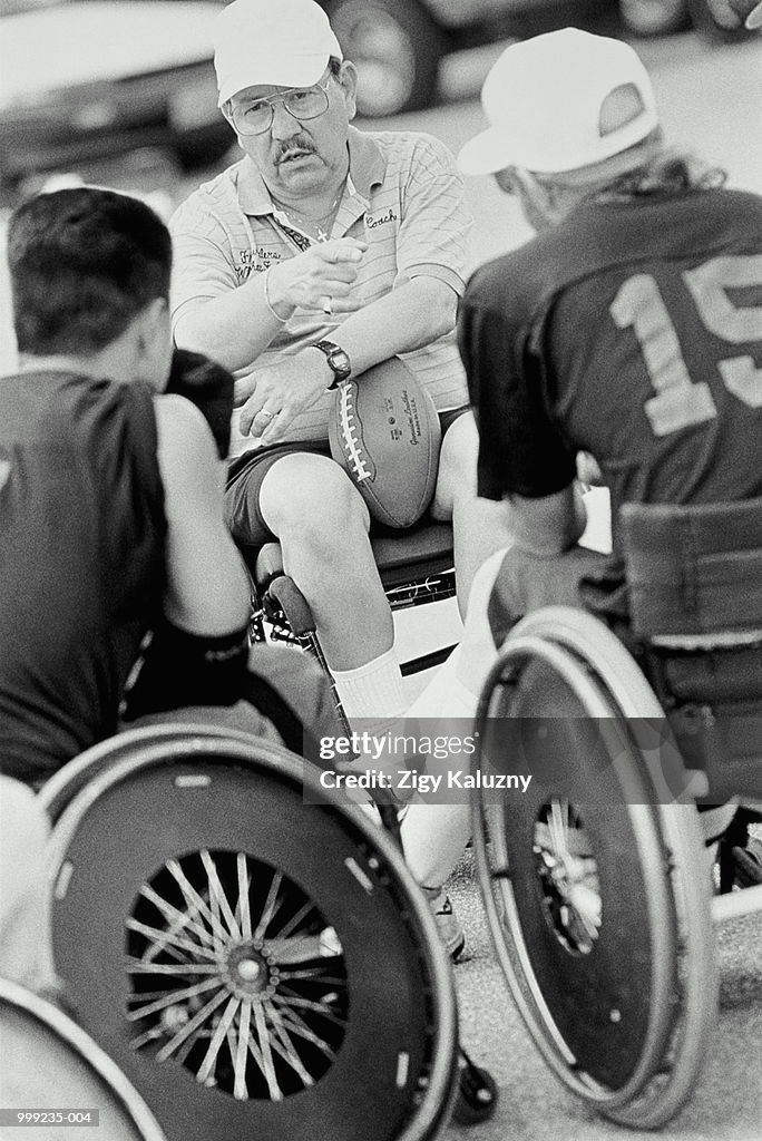 Wheelchair American football, coach talking to players (B&W)