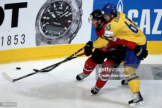 Steve Hirschi of Switzerland is challenged by Erik Karlsson of Sweden during the IIHF World Championship group E qualification round match between...