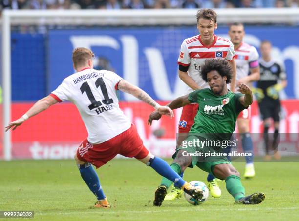 Hamburg's André Hahn and Albin Ekdal, and Augsburg's Caiuby vie for the ball during the German Bundesliga soccer match between Hamburger SV and FC...