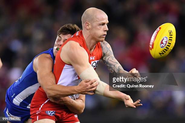 Zak Jones of the Swans handballs whilst being tackled by Nathan Hrovat of the Kangaroos during the round 17 AFL match between the North Melbourne...