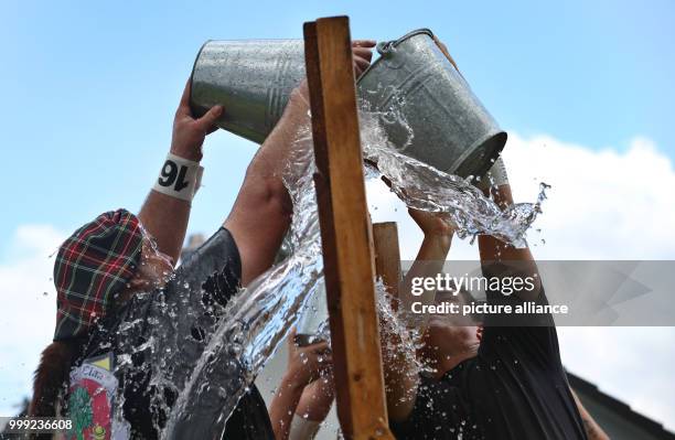 Participants of the Upper Swabian Highlandgames fill water in a bucket across a barrier in the discipline 'Most-Schöpfa ' in Horgenzell, Germany, 19...