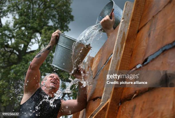 Participants of the Upper Swabian Highlandgames fill water in a bucket across a barrier in the discipline 'Most-Schöpfa ' in Horgenzell, Germany, 19...