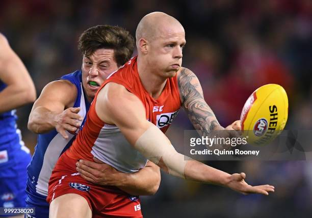 Zak Jones of the Swans handballs whilst being tackled by Nathan Hrovat of the Kangaroos during the round 17 AFL match between the North Melbourne...