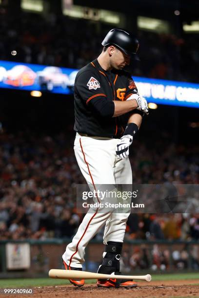 Buster Posey of the San Francisco Giants removes an elbow guard after he was walked by the Oakland Athletics during the ninth inning of their MLB...