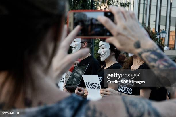 Woman is seen taking a picture of a protester wearing an anonymous mask during a demonstration by vegan activists for the 'voiceless' on Syntagma...