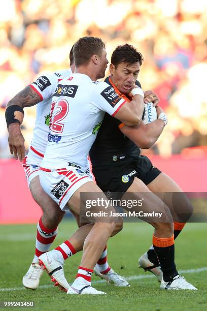 Elijah Taylor of the Tigers is tackled by Tariq Sims of the Dragons during the round 18 NRL match between the St George Illawarra Dragons and the...