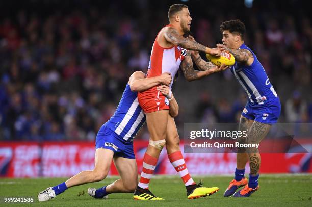 Lance Franklin of the Swans handballs whilst being tackled by Scott Thompson and Marley Williams of the Kangaroos during the round 17 AFL match...