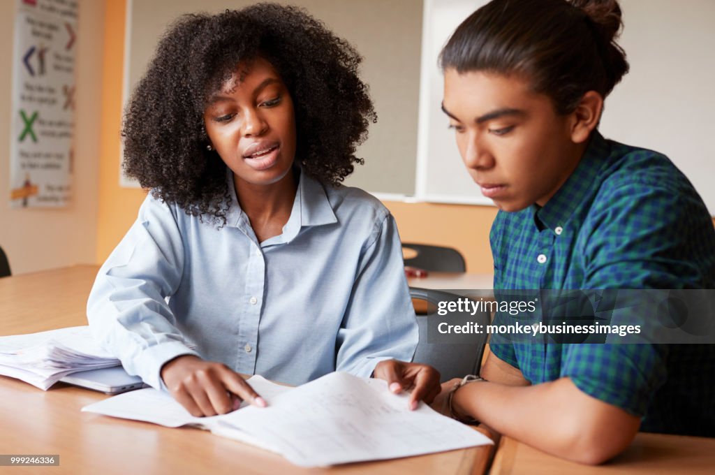 Tutor de colegial dando aulas de um para um estudante do sexo masculino na mesa