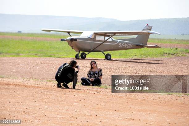 man photographing woman in front of the plane at masai mara airport - 1001slide stock pictures, royalty-free photos & images