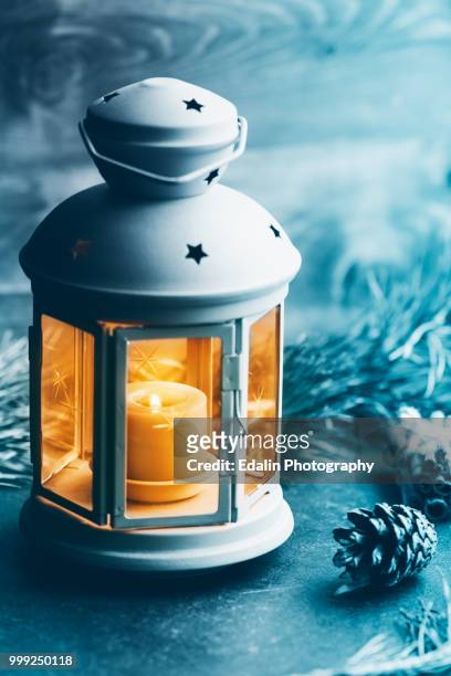 close-up photo of a blue vintage lantern with burning candle among christmas decoration. concept... - teelicht stock-fotos und bilder