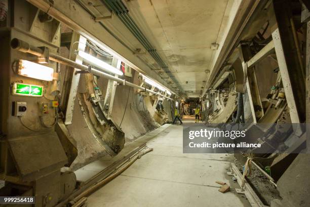 Two people walking past the front section of the tunnel drilling machine in a section of construction site for the Brenner Base Tunnel near...