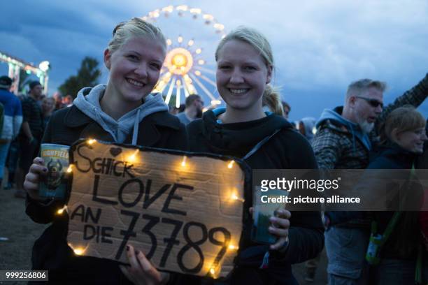 Two attendees hold up a sign with a string of fairy lights in the middle of the crowd at Highfield Festival in Grosspoesna, Germany, 20 August 2017....