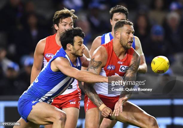 Lance Franklin of the Swans handballs whilst being tackled by Scott Thompson of the Kangaroos during the round 17 AFL match between the North...