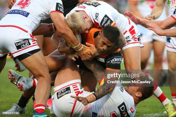 Michael Chee Kam of the Tigers is tackled by Gareth Widdop of the Dragons and Tariq Sims of the Dragons during the round 18 NRL match between the St...