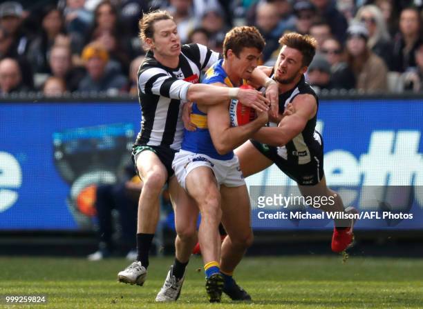 Jamie Cripps of the Eagles is tackled by Tom Langdon of the Magpies and Tom Phillips of the Magpies during the 2018 AFL round 17 match between the...