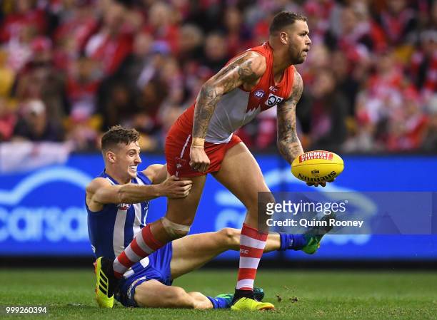 Lance Franklin of the Swans handballs whilst being tackled by Shaun Atley of the Kangaroos during the round 17 AFL match between the North Melbourne...