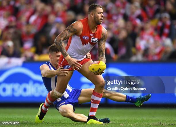 Lance Franklin of the Swans handballs whilst being tackled by Shaun Atley of the Kangaroos during the round 17 AFL match between the North Melbourne...