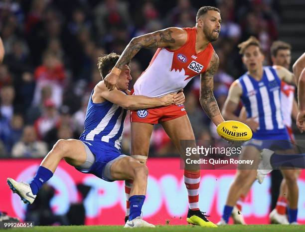 Lance Franklin of the Swans handballs whilst being tackled by Shaun Higgins of the Kangaroos during the round 17 AFL match between the North...
